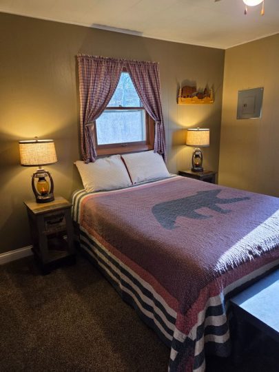 Cozy rustic cabin bedroom with bear-themed blanket and lantern lamps