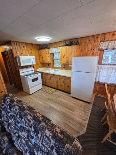 Cozy rustic cabin kitchen with wood paneling and white appliances