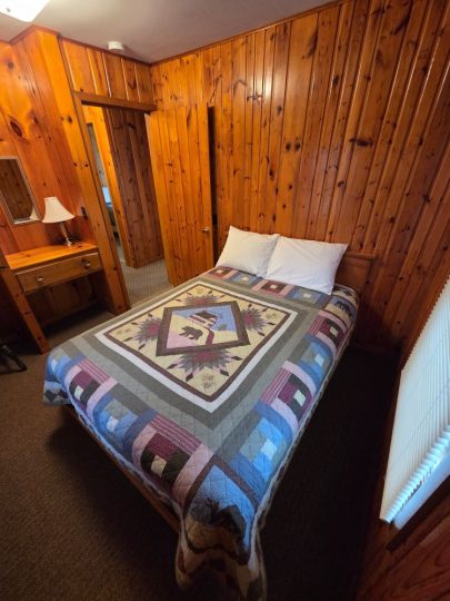 Cozy cabin bedroom with patchwork quilt and wood paneling