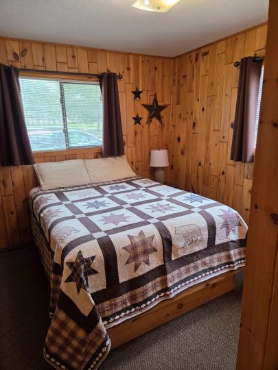 Rustic cabin bedroom with star quilt and wood-paneled walls