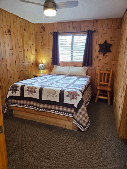 Cozy rustic cabin bedroom with bear quilt and wood walls