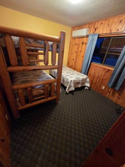 Rustic cabin bedroom with log bunk beds and twin bed