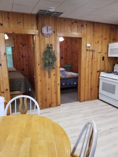 Cozy wood-paneled cabin interior with kitchen and two bedrooms