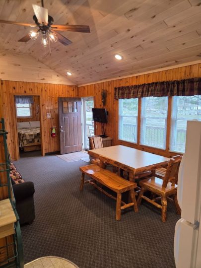 Cozy rustic cabin interior with wooden dining set and ceiling fan