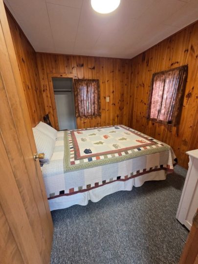 Cozy cabin bedroom with knotty pine walls and quilt bedding