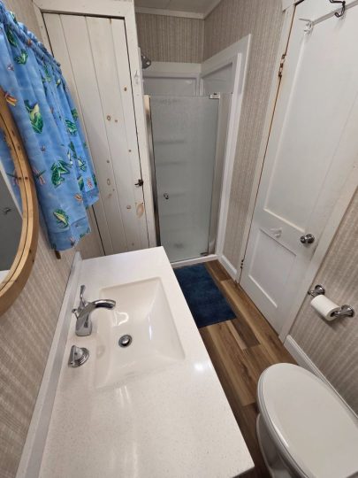 Small bathroom with sink, toilet, and glass shower stall