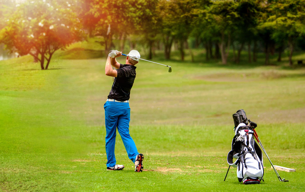 Golfer completing swing on lush green golf course