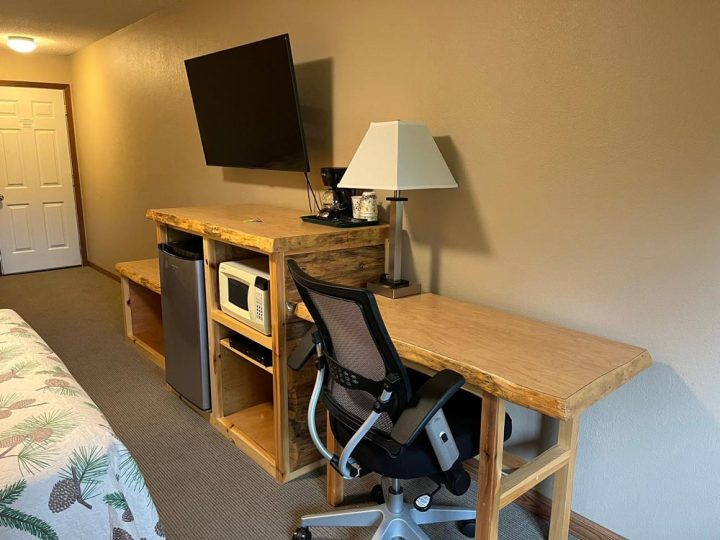Rustic hotel room with wooden desk, TV, and amenities